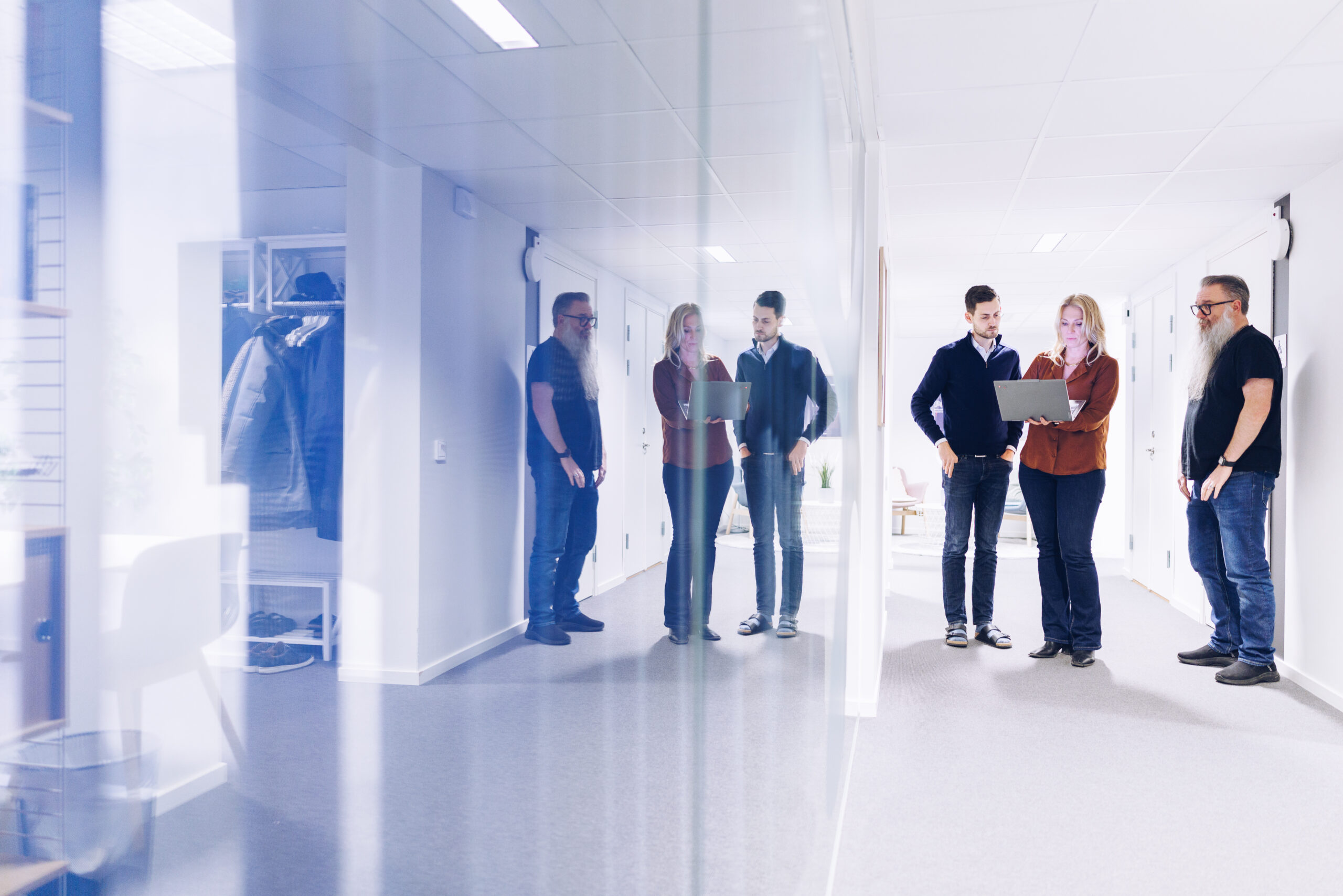 Bilden visar ett team som pratar med varandra stående med en dator till hands. Teamet befinner sig på Softhouse